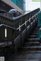 A woman in a green coat is walking up some stairs.