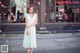 A woman in a white dress standing in front of a building.