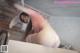 A woman in a pink shirt and white stockings is posing on a bed.