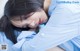 A woman in a blue shirt laying on a bed.