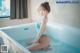 A woman in a blue bathing suit sitting in a bathtub.