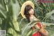 A woman in a straw hat standing in a corn field.