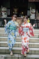 Two women in kimonos are walking up some steps.