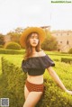 A woman in a straw hat sitting on a hedge.