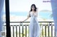 A woman in a white dress standing on a balcony.