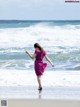 A woman in a pink dress running on the beach.